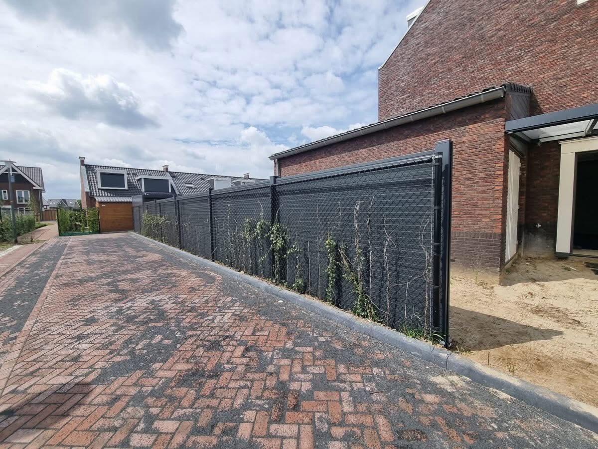 Antraciet aluminium wand als erfafscheiding langs een tuinpad