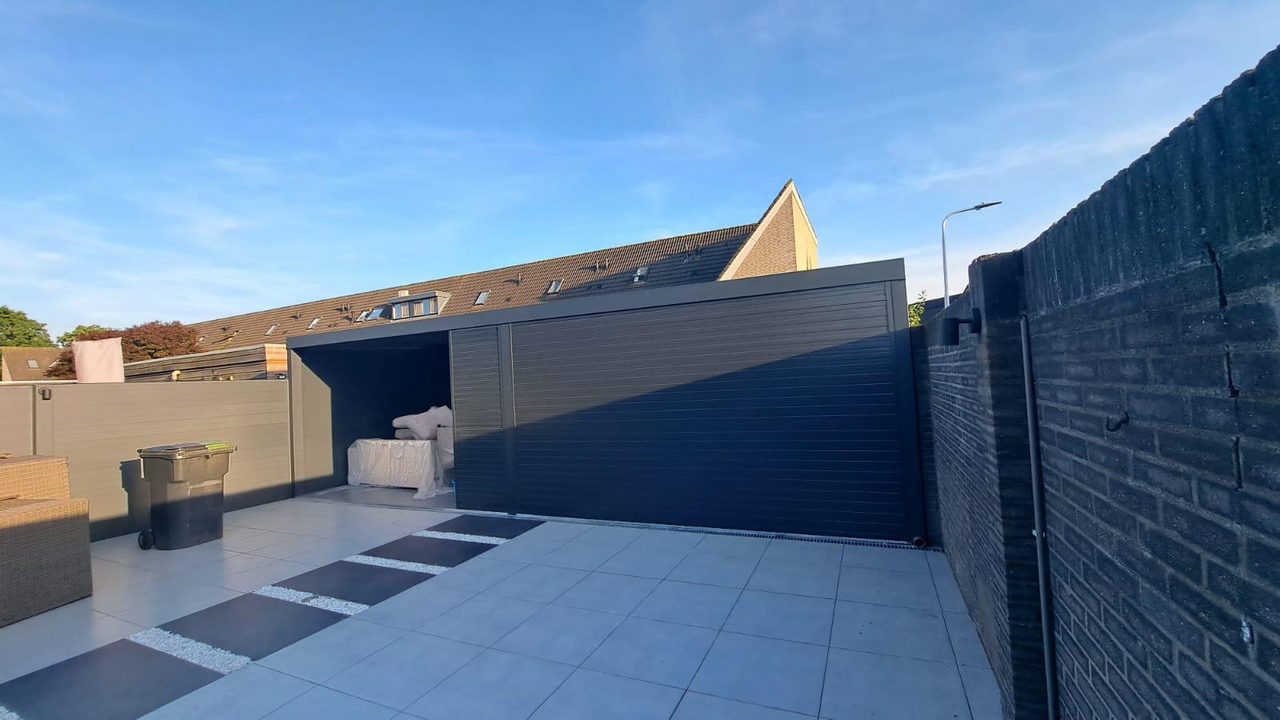 Antraciet aluminium wand rond een tegelterras met overkapping