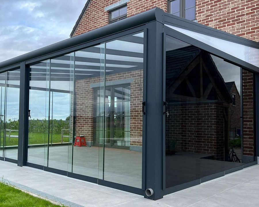 Hoek van een tuinkamer met glazen schuifwanden en zicht op het weiland
