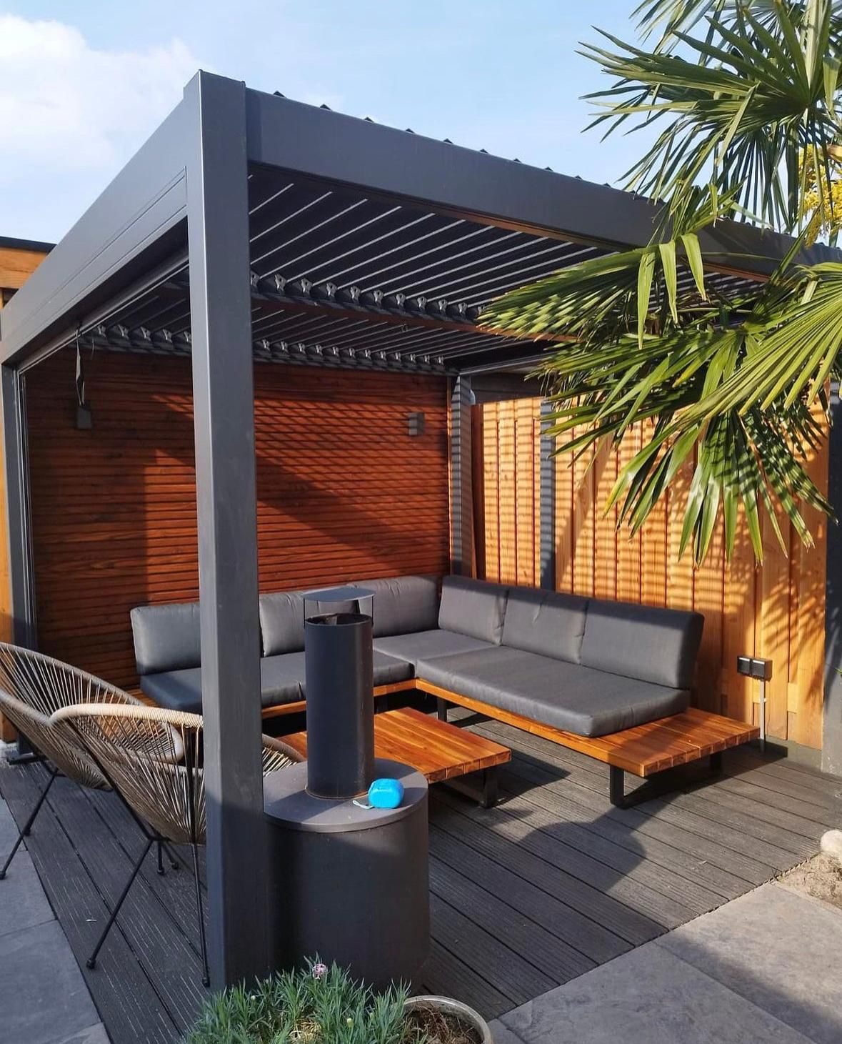 Lamellendak boven een loungebank naast een palmboom