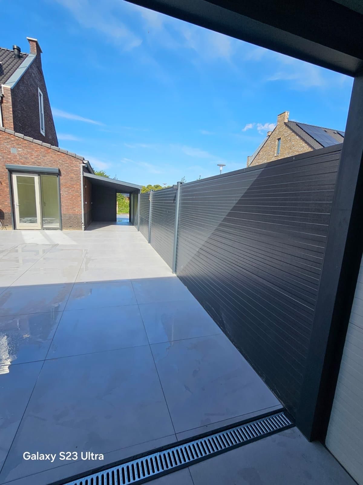 Zijpad met antraciet keramische tegels en een aluminium schutting