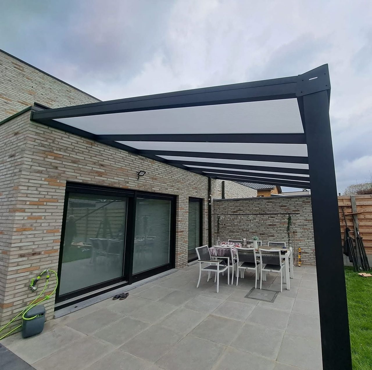 Terrasoverkapping met opaal dak aan een bungalow van gele baksteen