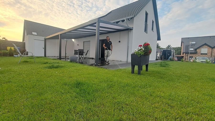 Overkapping aan een witte woning met groot gazon in avondlicht