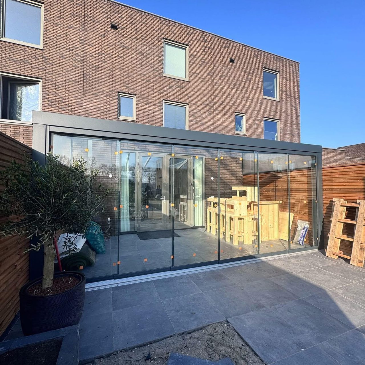 Tuinkamer met glazen schuifwanden aan een bakstenen rijtjeshuis
