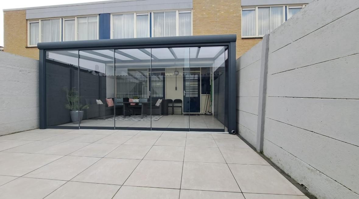 Tuinkamer met glazen schuifwanden in een betegelde stadstuin