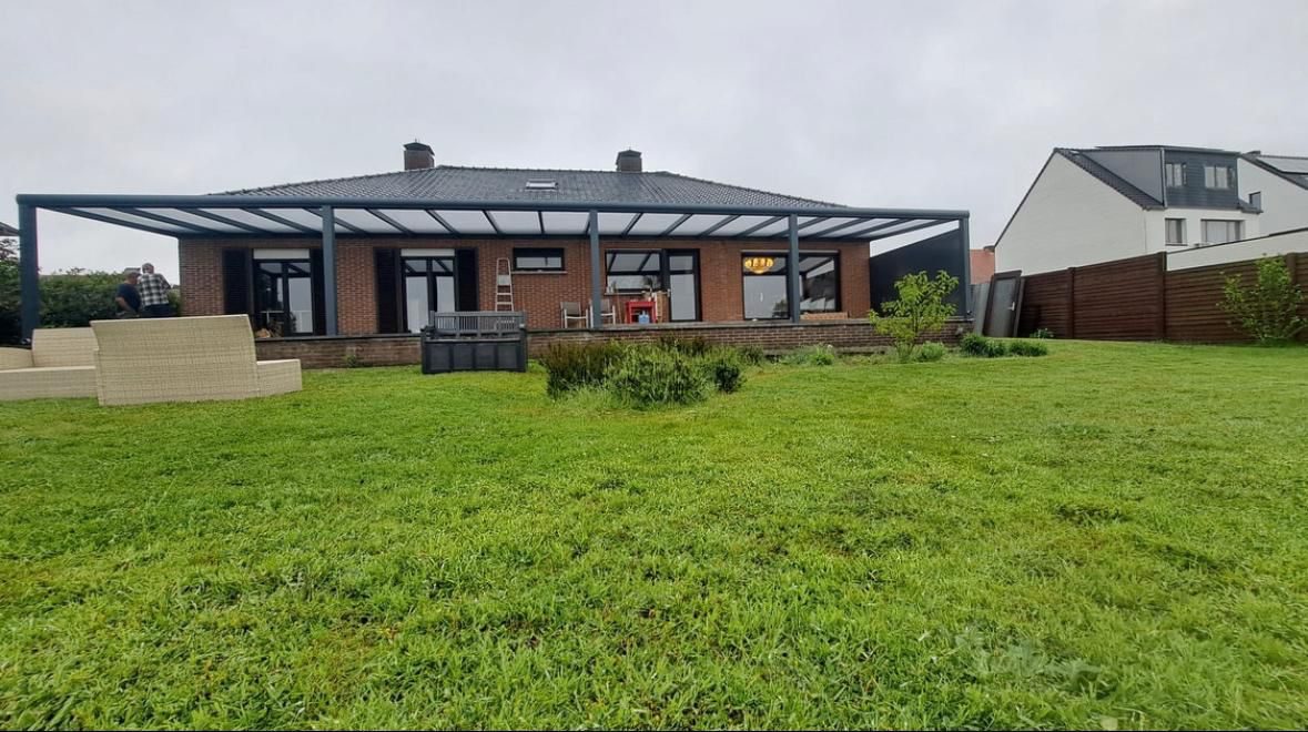 Zeer brede overkapping langs een bungalow met groot gazon