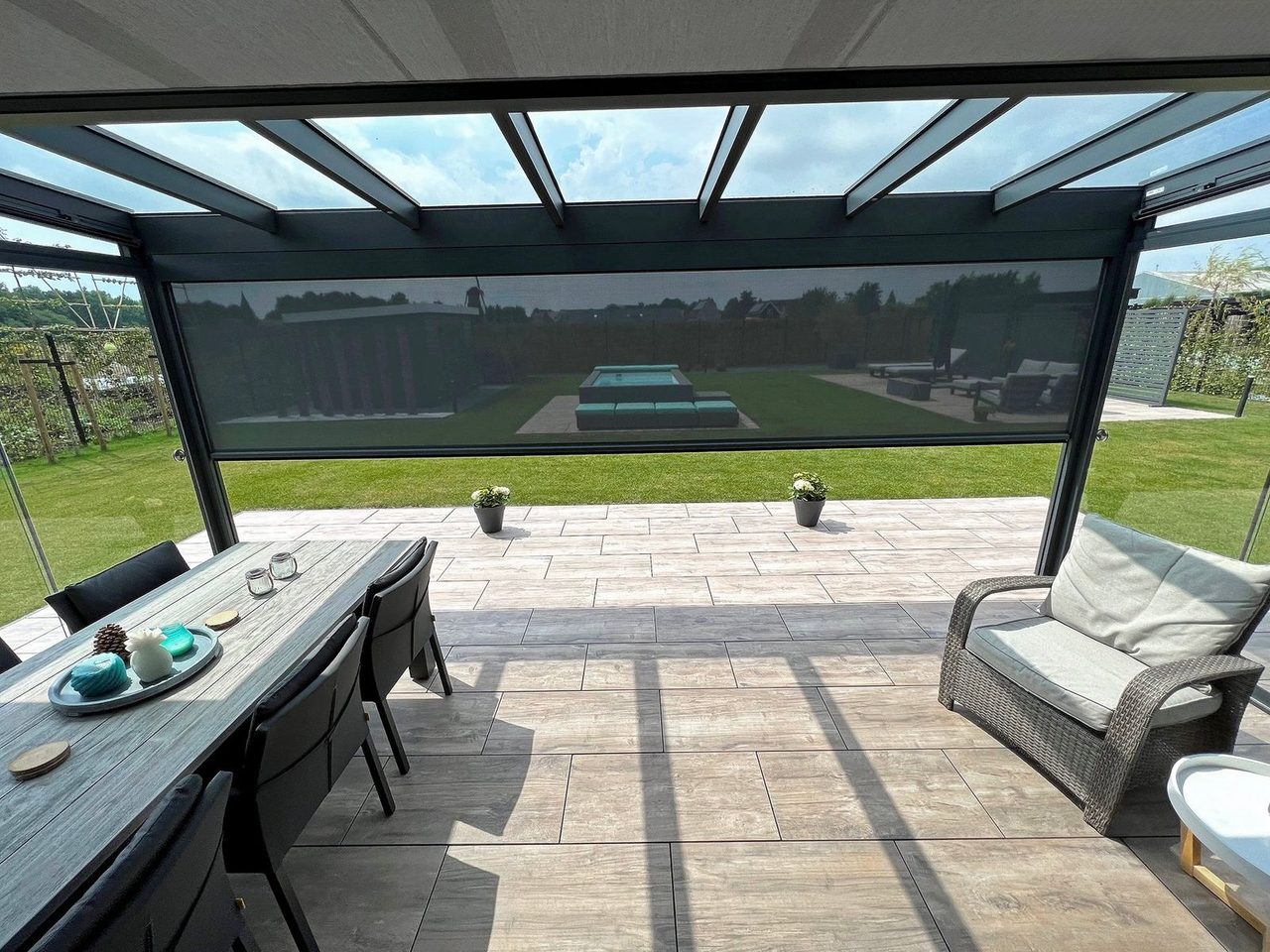 Zicht vanonder een glazen veranda op een screen en de tuin